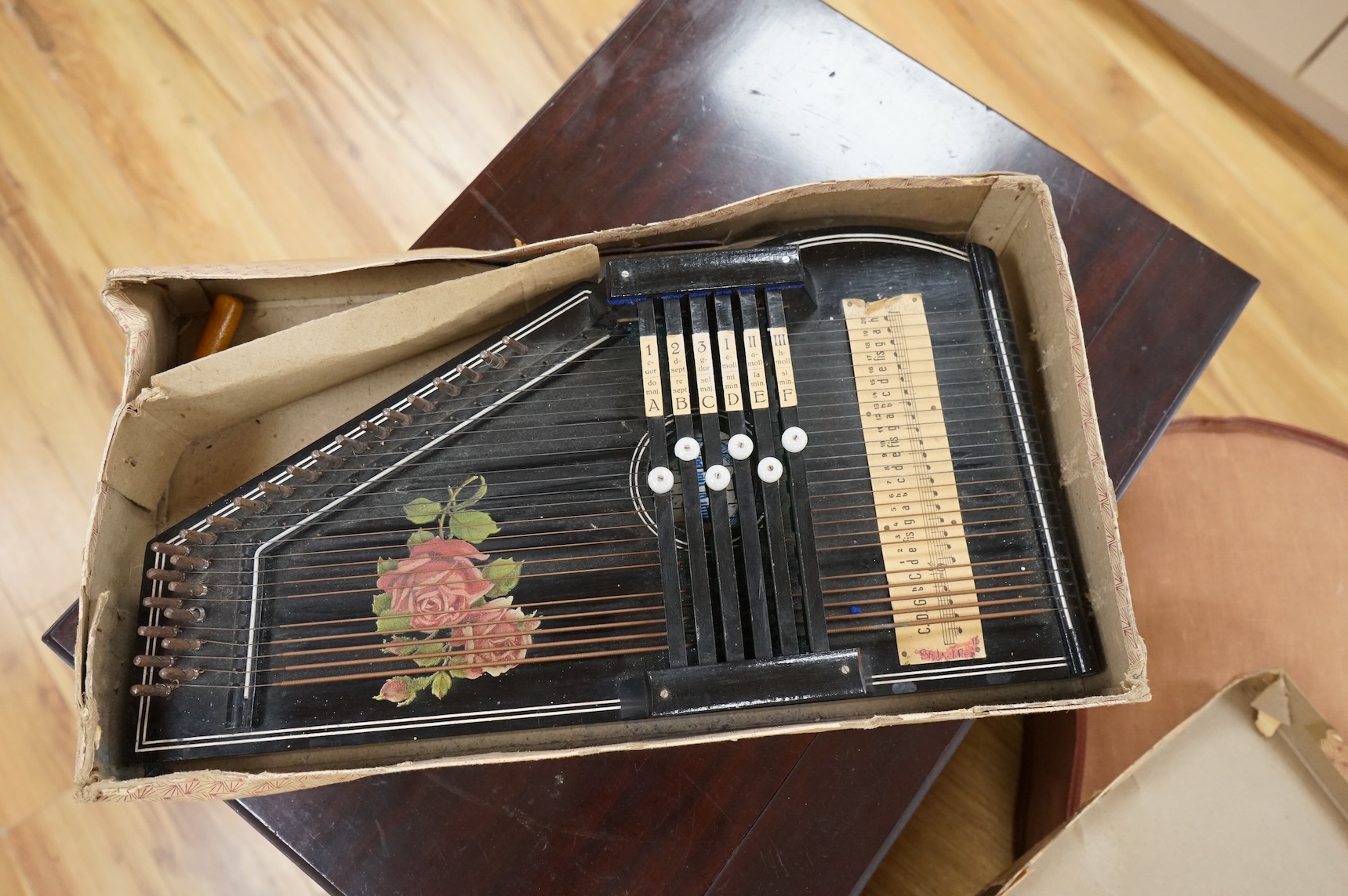 A late 19th century Monopol disc music box in a mahogany case, to play discs 19cm diameter, together with twelve discs, plus an ebonised ‘Chord-Harps’ zither in its original card box with tuning hammer.
